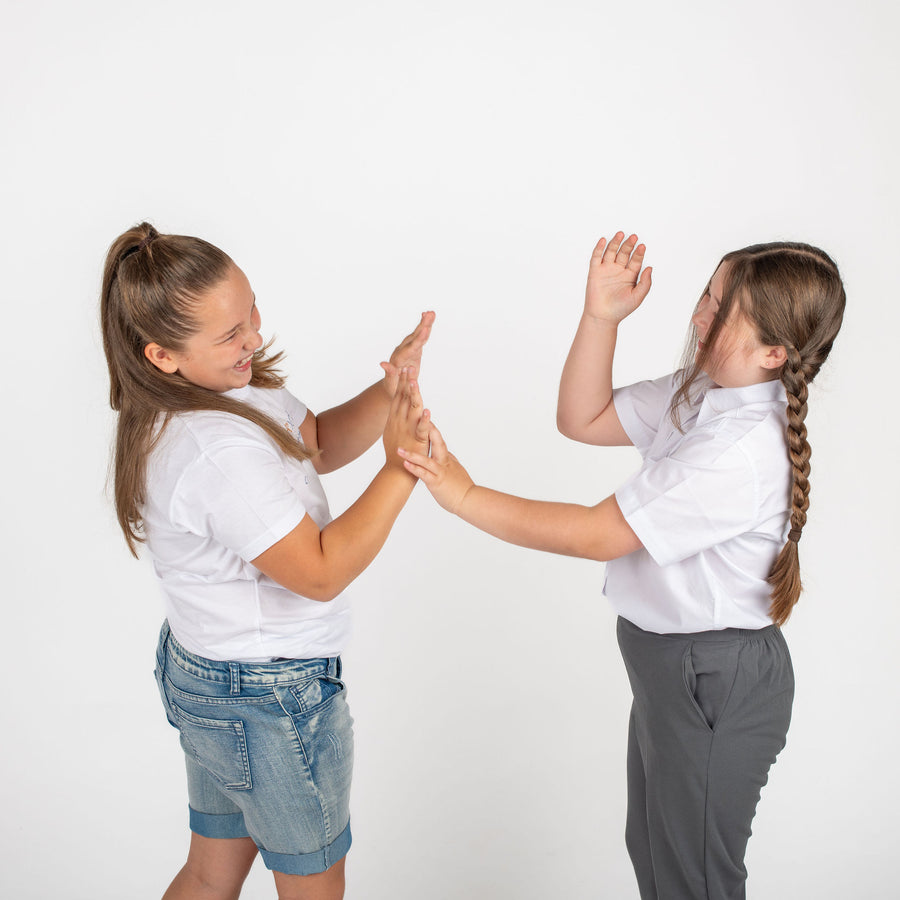 Two girls high-fiving in Sturdy Kids school uniform and casual wear, plus fit school uniform for ages 2 to 16